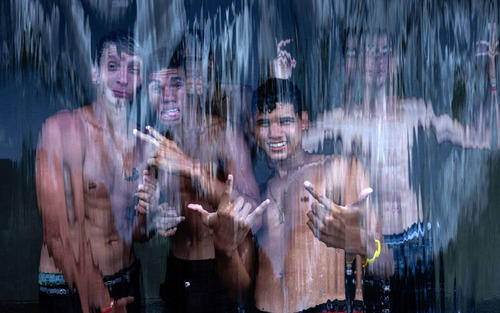 نوجوانان برزیلی زیر یک آبشار اب در گرمای تابستانی شهر ریودوژانیرو