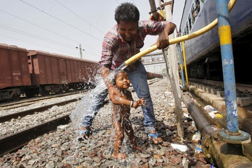 شستشوی یک کودک هندی با مخزن آب یک قطار (ایستگاه قطار الله آباد)