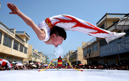 حرکات و انعطاف بدنی عجیب یک پسر 6 ساله چینی در حال اجرای نمایش در شهر بوژو. تکیه وزن این کودک در این حرکت روی دندان هایش است