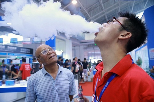 یک فروشنده محصول جدید سیگار الکترونیک در جریان نمایشگاهی در پکن در حال تبلیغ و نمایش محصول تولیدی جدید