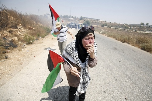 معترضان فلسطینی در کرانه غربی در حال سرفه کردن به خاطر شلیک گلوله های گاز اشک آور نیروهای اسراییلی