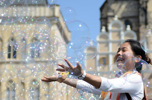 یک توریست آسیایی در حال بازی با حباب در میدان قدیمی شهر پراگ – جمهوری چک