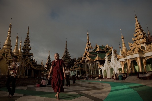 راهب بودایی در حال عبور از مقابل یک معبد در شهر رانگون میانمار