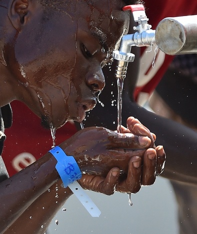 مهاجر آفریقایی تبار پس از رسیدن به جزیره سیسیل ایتالیا در حال نوشیدن آب