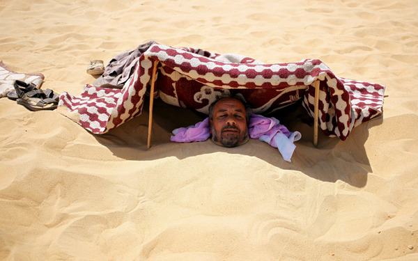 یک مرد مصری برای درمان بیماری خود زیر شن های صحرای سیوا در غرب مصر خوابیده است