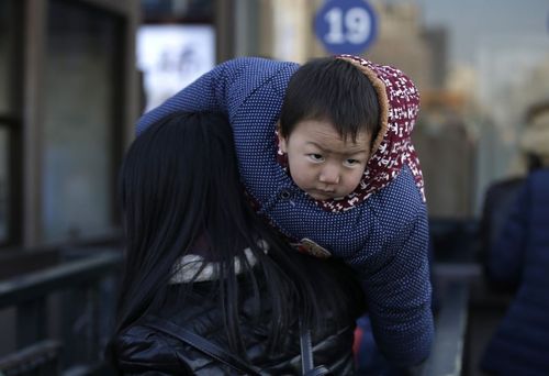 مادر و فرزند در حال سوار شدن به قطار در ایستگاه قطار پکن