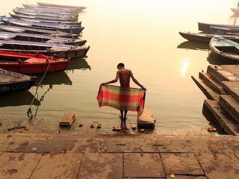 یک مرد هندو در حال انجام آیین آب تنی در حاشیه رود گنگ در واراناسی هند