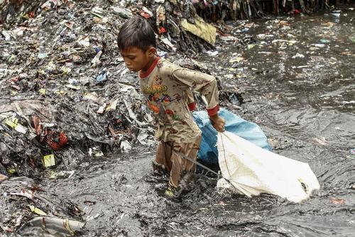 کودک کار اندونزیایی در حال جمع کردن زباله از رودخانه
