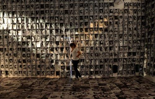 یک زن ایستاده در میان تصاویر قربانیان نقض حقوق بشر در موزه ای در شهر مانیل پایتخت فیلیپین