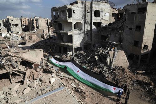 مخالفان مسلح حکومت سوریه پرچم سابق این کشور را در ویرانه های شهر جُبار در حومه شرقی دمشق پهن کرده اند