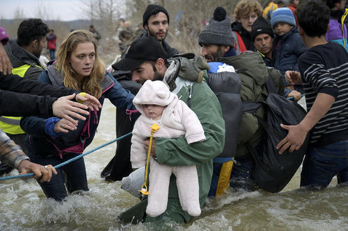 پناهجویان خاورمیانه ای در حال عبور از عرض یک رودخانه پس از گذشتن از مرز یونان و مقدونیه