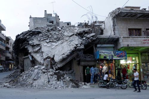 یک بوتیک لباس فروشی در کنار ساختمان ویران شده از جنگ در شهر مارت النعمان در استان ادلب سوریه که در کنترل شورشان مخالف حکومت است