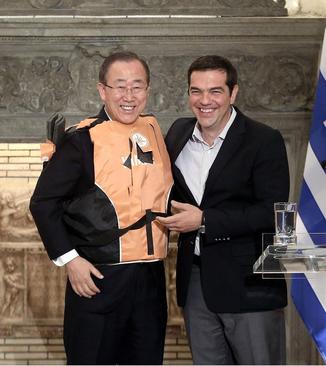 بستن جلیقه نجات پناهجویان به بان کی مون دبیر کل سازمان ملل در جریان دیدار او با الکسیس سیپراس نخست وزیر یونان در آتن. دبیر کل سازمان ملل به منظور بررسی وضعیت پناهجویان به یونان سفر کرده است