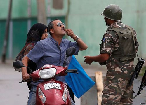 مردی در سرینگر کشمیر در حال نشان دادن دندان خود به پلیس است تا از محدودیت های ترافیکی عبور کرده و به دکتر برود