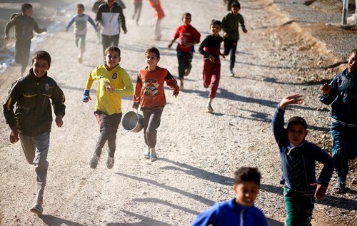 دویدن کودکان به دنبال ماشین توزیع غذا در اردوگاه آوارگان جنگی در عراق