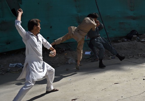 معترضان افغان در حال کتک زدن یک نیروی پلیس پس از واقعه 3 انفجار انتحاری در تظاهرات مسالمت آمیز جنبش روشنایی در کابل