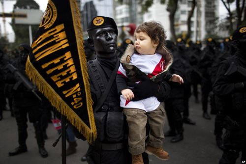 سرباز ارتش پرو پیش از انجام رژه روز استقلال این کشور در شهر لیما در حال گرفتن یک عکس یادگاری با یک کودک است