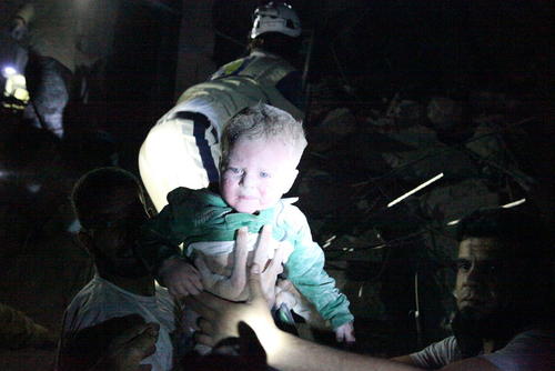 بیرون کشیدن یک نوزاد از زیر آوار بمباران هوایی در شهر حلب سوریه